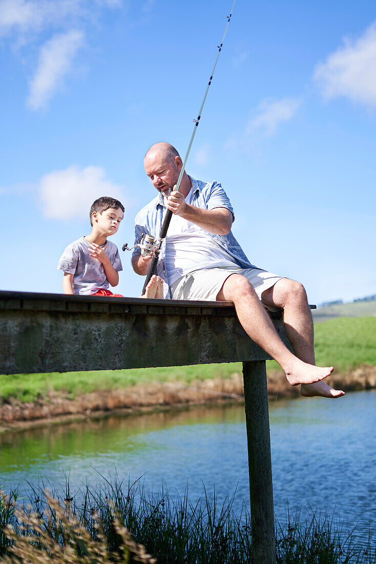 Father and son with Down syndrome fishing on summer dock