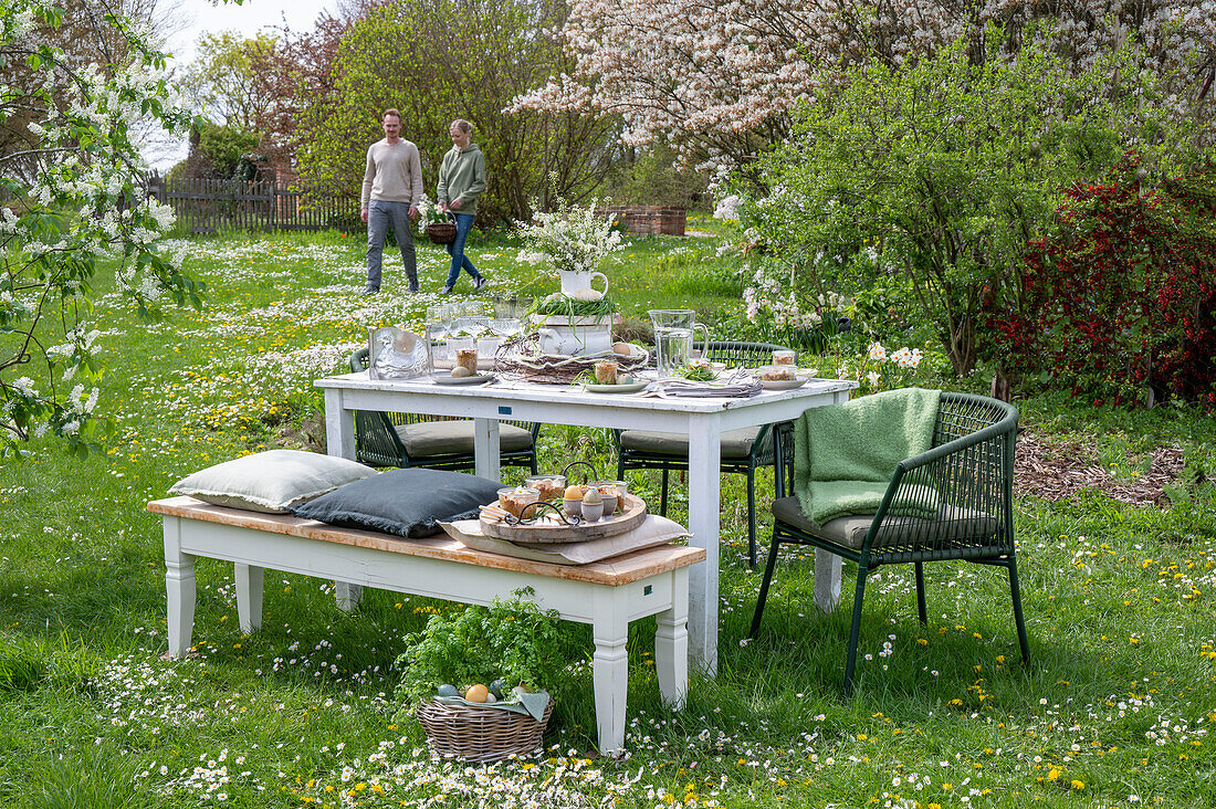 Young couple in background of laid table for Easter breakfast in the garden