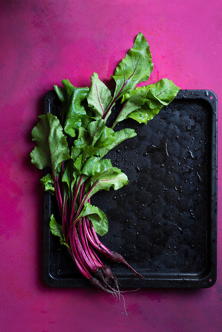 Beetroot on a black tray with drops of water