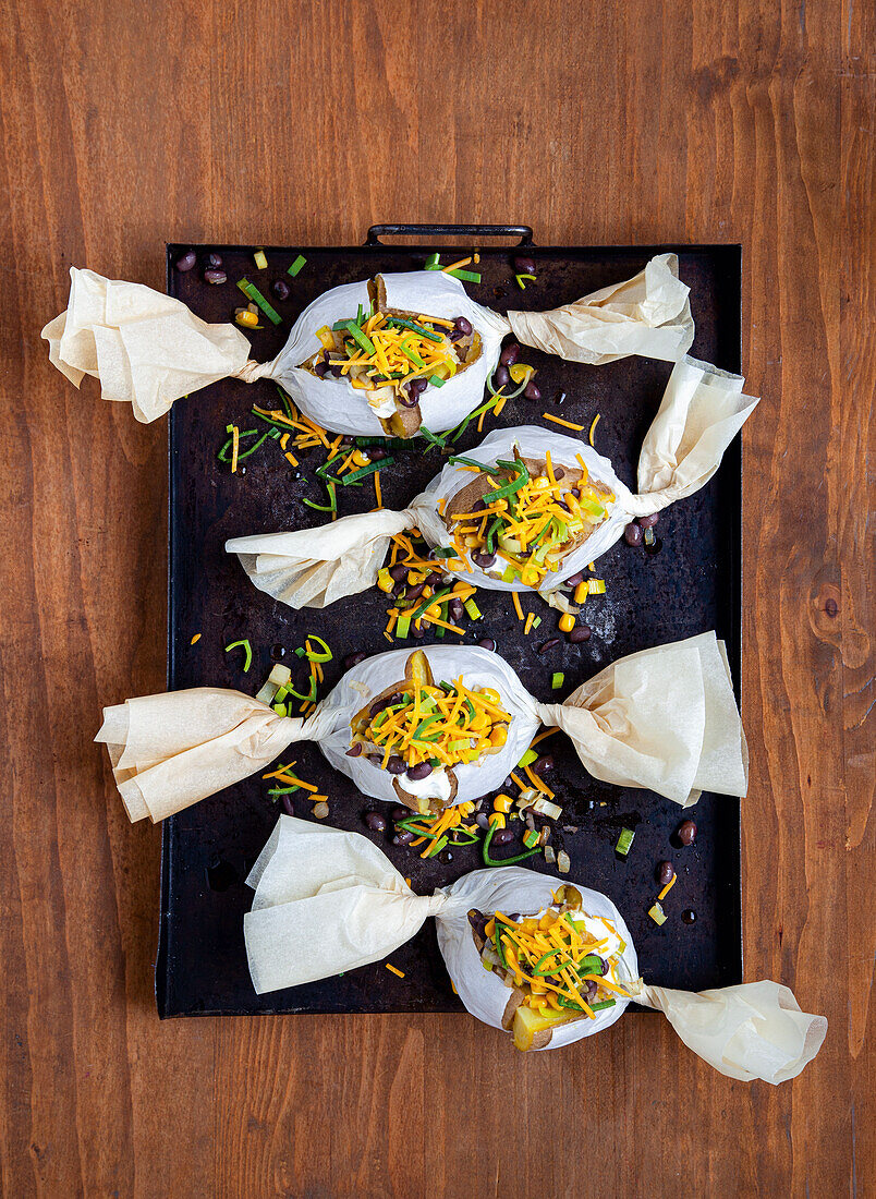 Baked potatoes with bean filling and cheddar in parchment paper