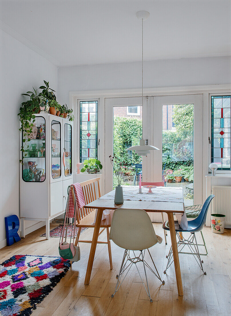 Dining area with wooden table, bench, chairs and colourful rug