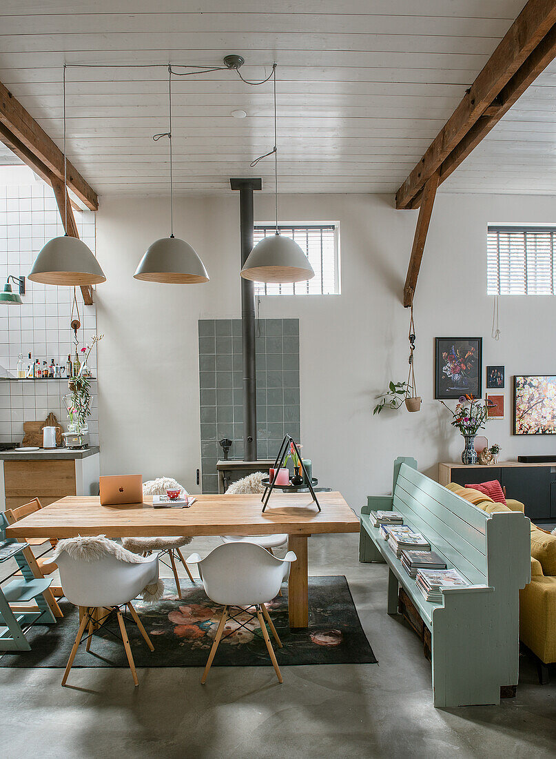 Dining room with wooden table, white chairs, mint green bench and fireplace