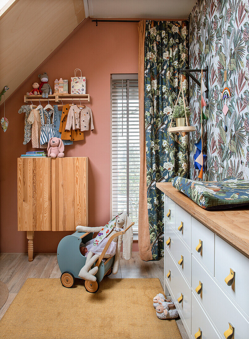 Children's room with chest of drawers, colorful wallpaper and doll's pram