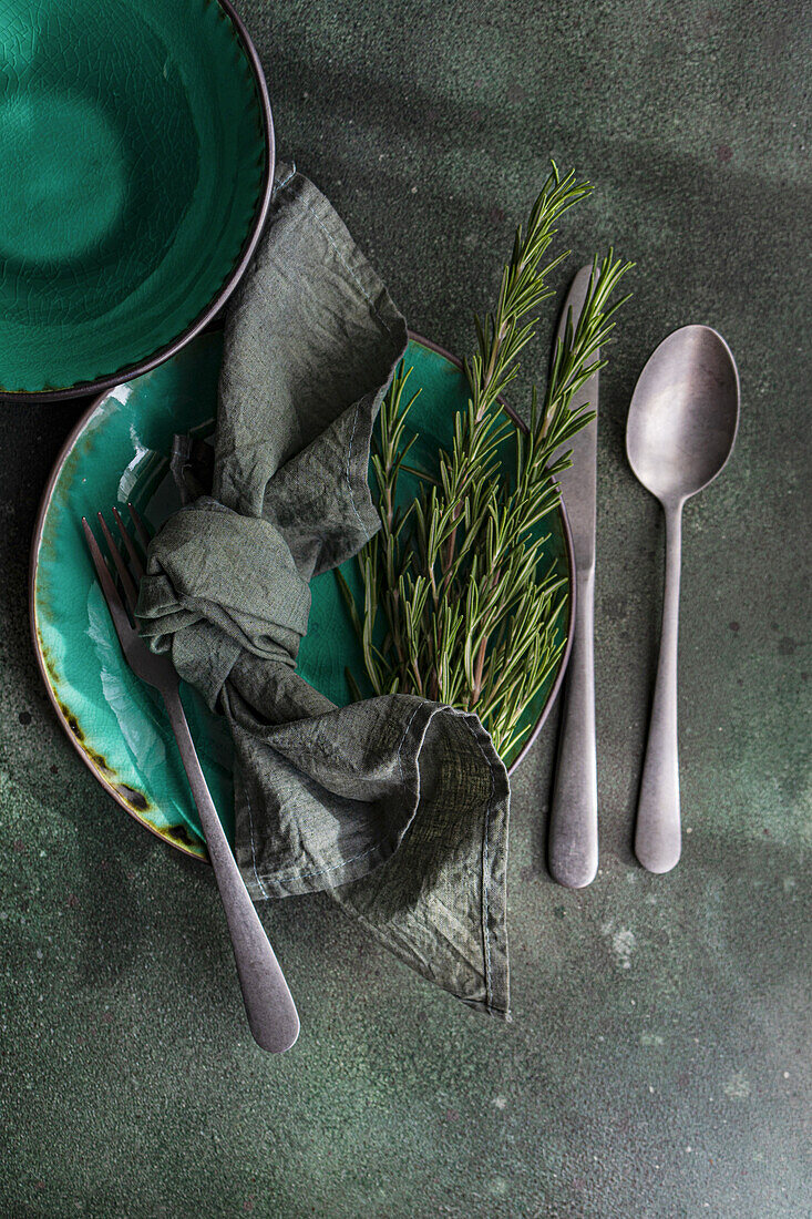 Provençal table setting with rosemary and fabric napkin in shades of green
