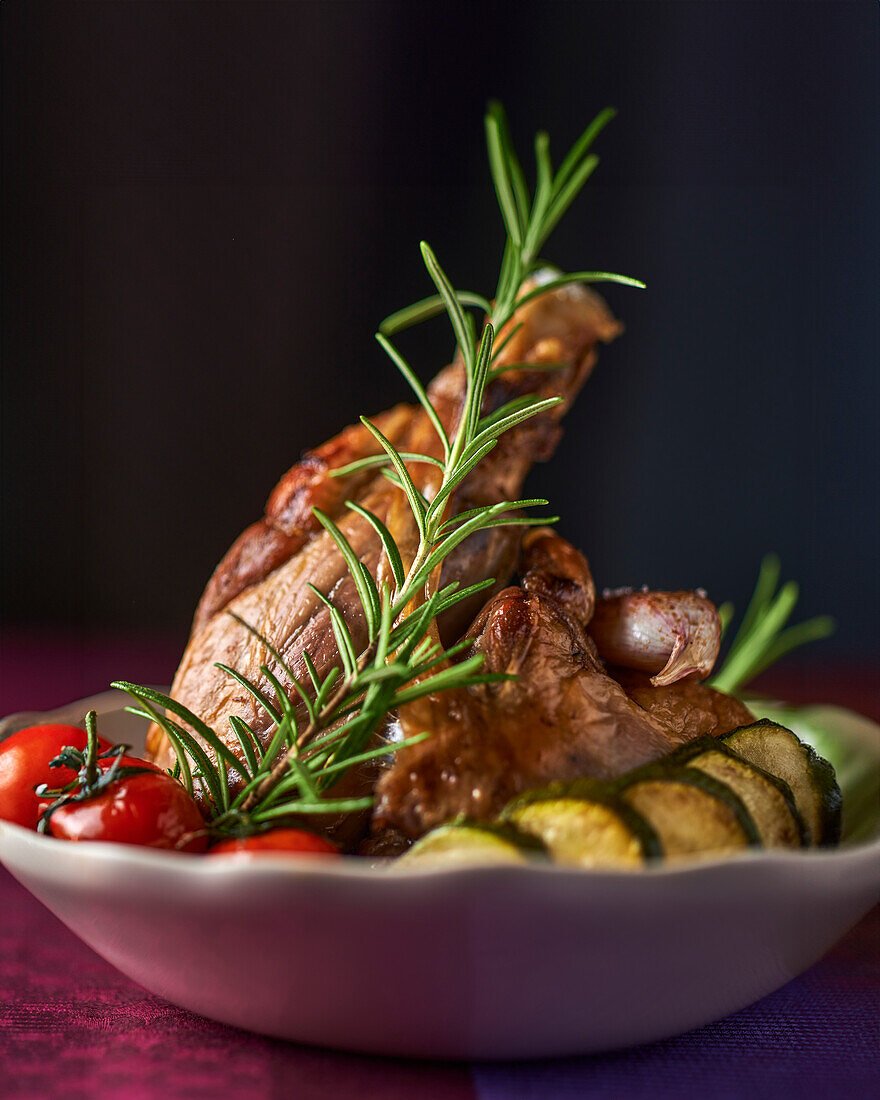 Roasted leg of lamb with rosemary, courgettes and tomatoes