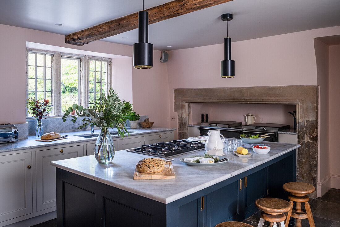 Kitchen with cooking island, wooden chairs and beamed ceiling