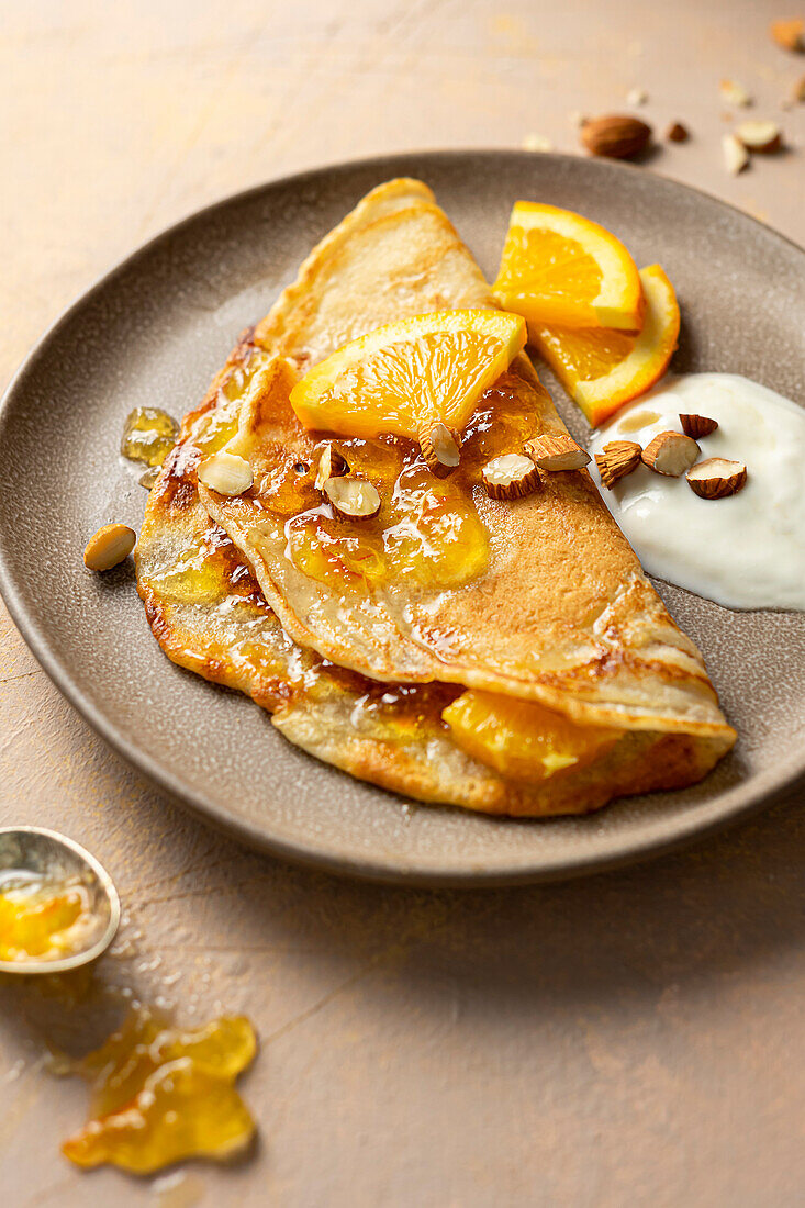 Pancakes with jam, yoghurt, almonds and oranges