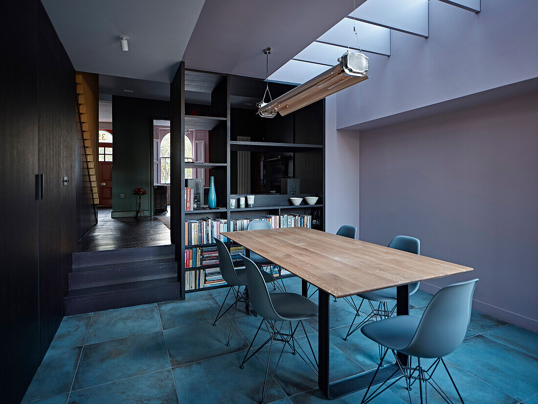 Dining area with long table, designer chairs and shelving as a room divider