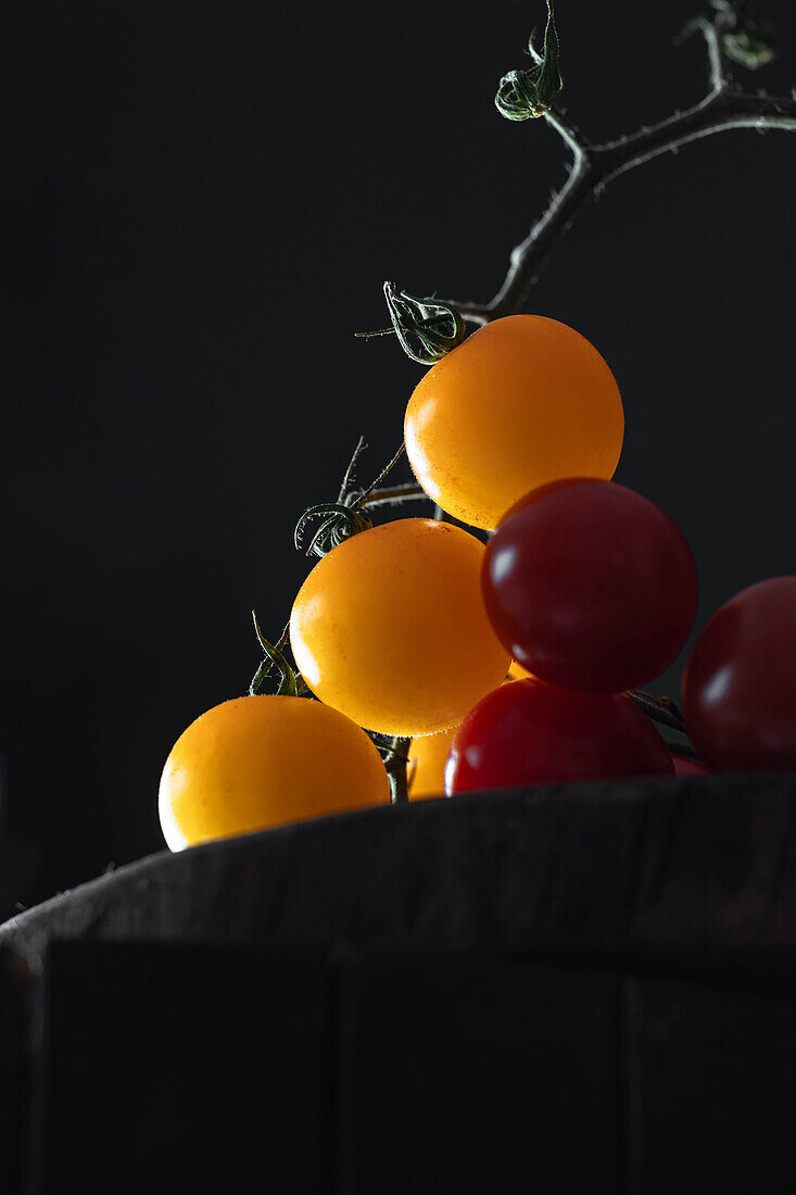 Yellow and red cherry tomatoes against a black background
