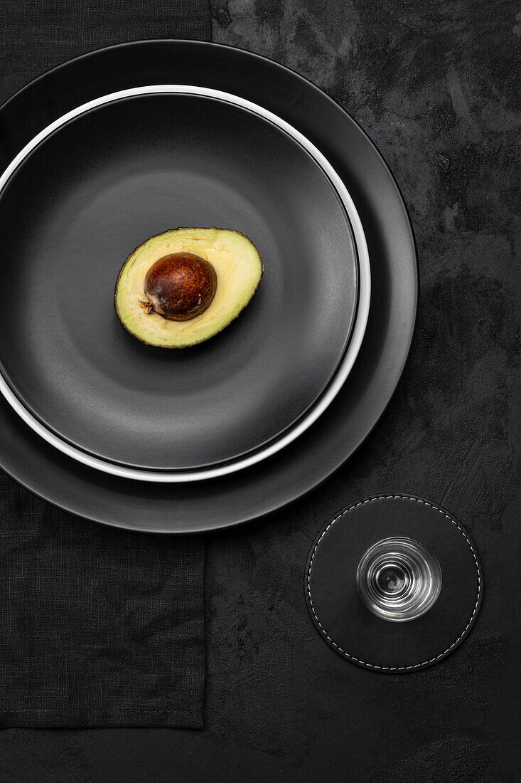 Half an avocado on black plates