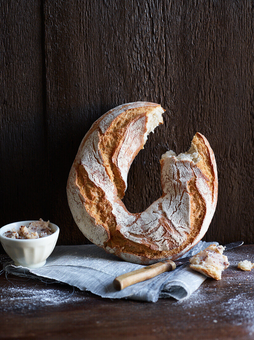 Ring-shaped light-coloured bread, one piece broken out