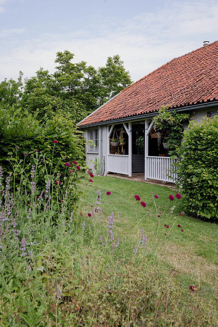 Detached house with veranda, surrounded by lush garden and flowering perennials