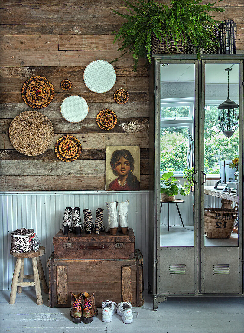 Eingangsbereich mit Holzkisten, Wandschmuck und Schuhen vor Holzverkleidung