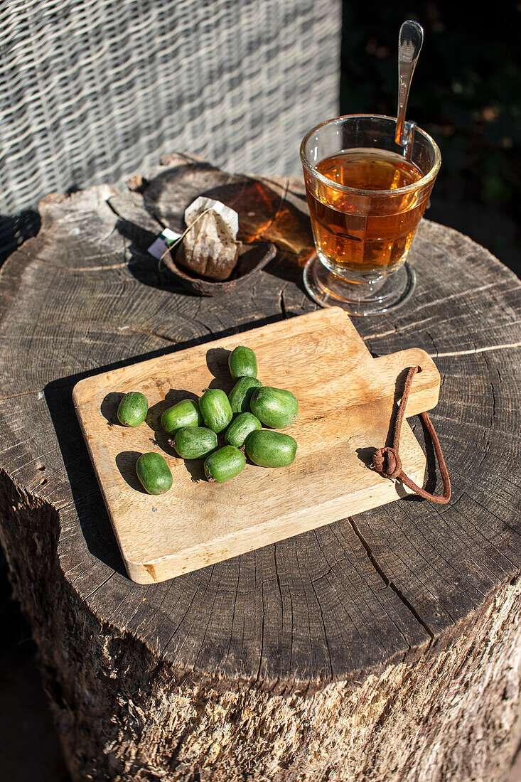 Tee und frische Kiwi-Beeren auf rustikalem Holzbrett im Garten