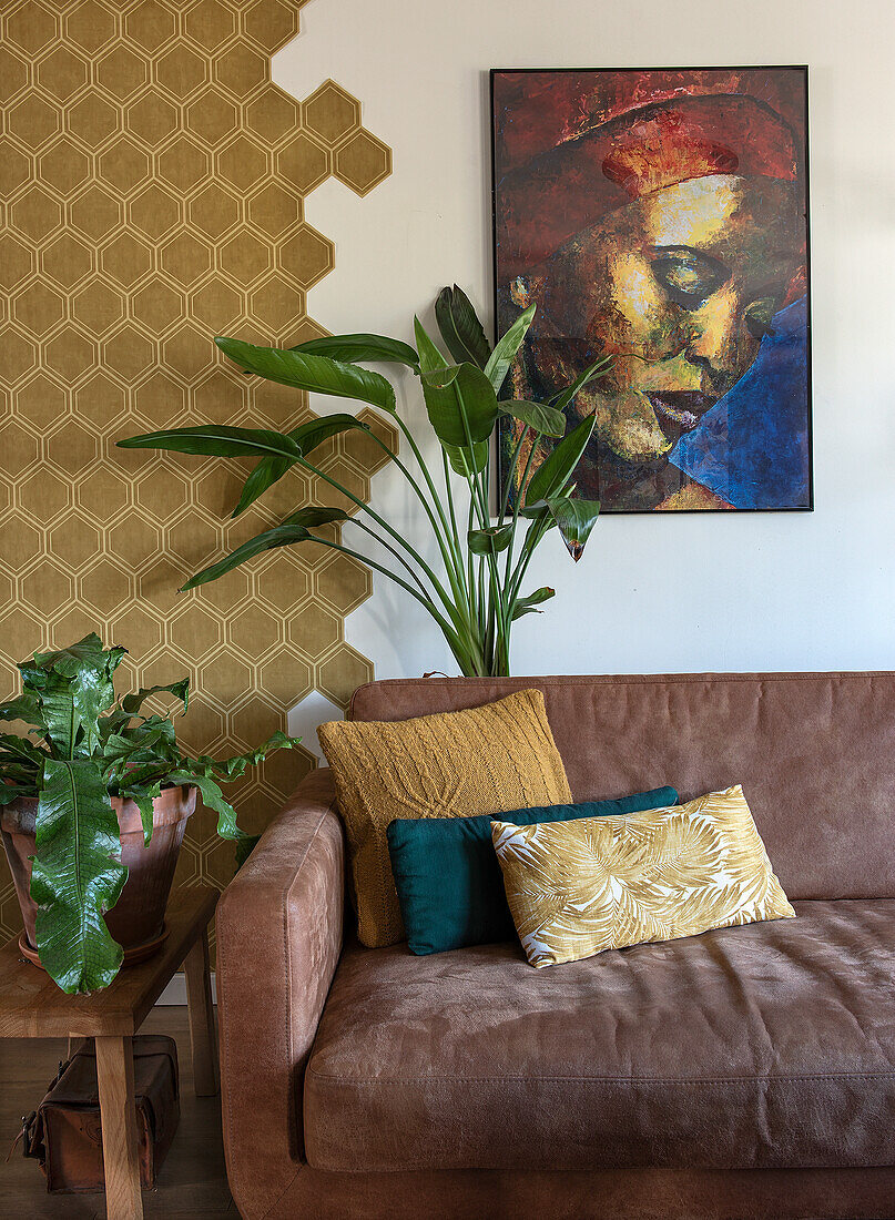 Brown leather sofa with patterned cushions and plants in front of decorative wall design