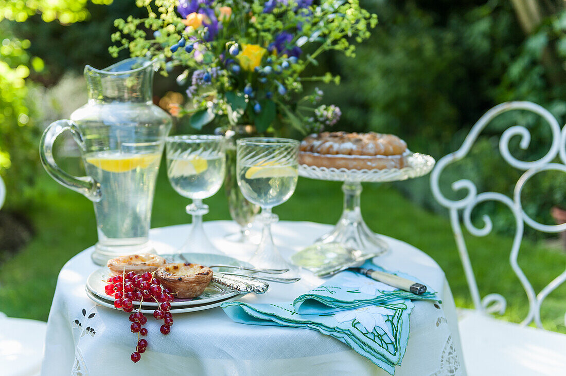 Summer garden table with cake, cupcakes and lemon water