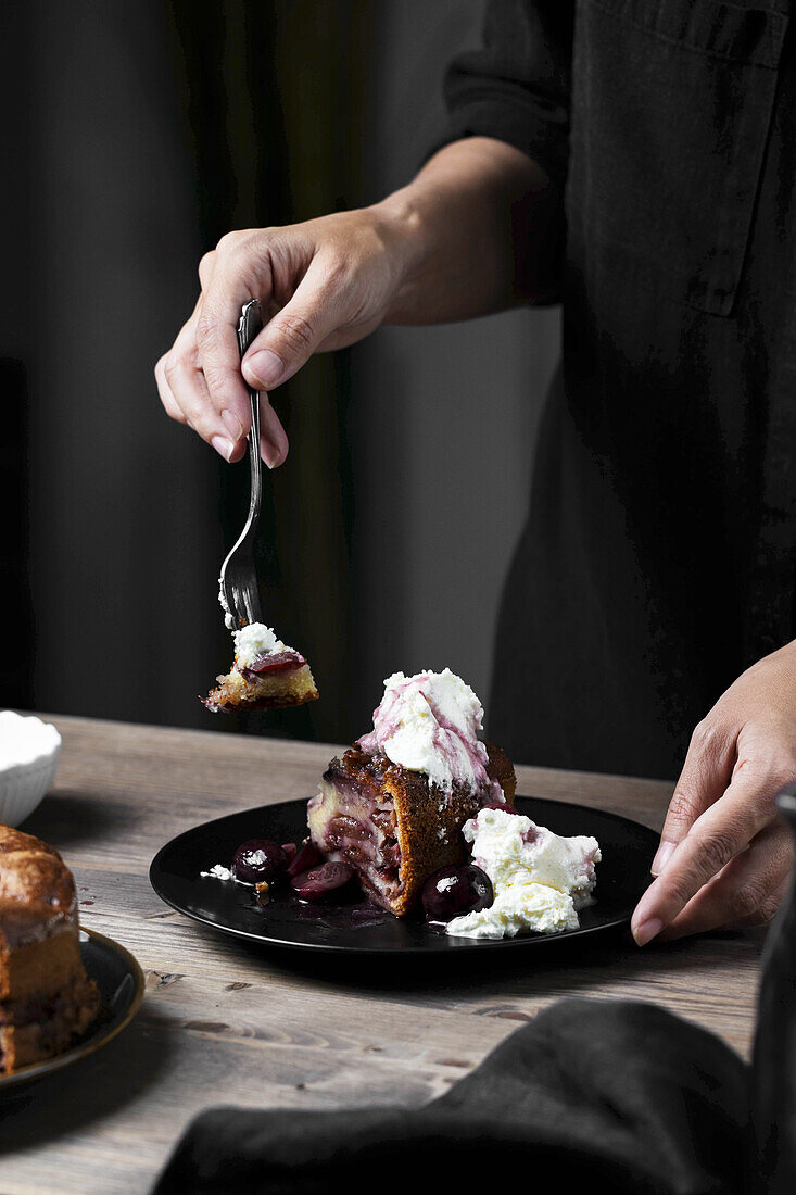 Frau isst Pflaumenkuchen mit Kompott und Sahne