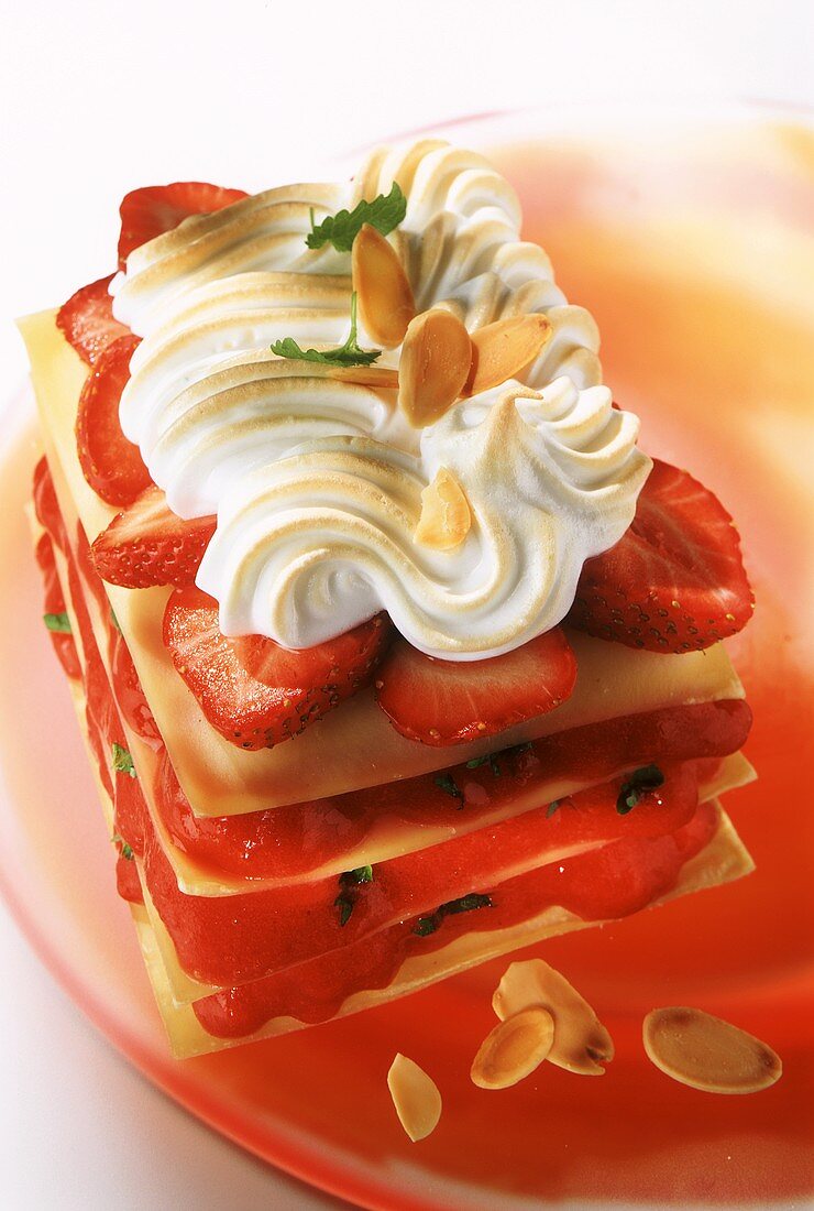 Strawberry lasagna with meringue topping on red glass plate