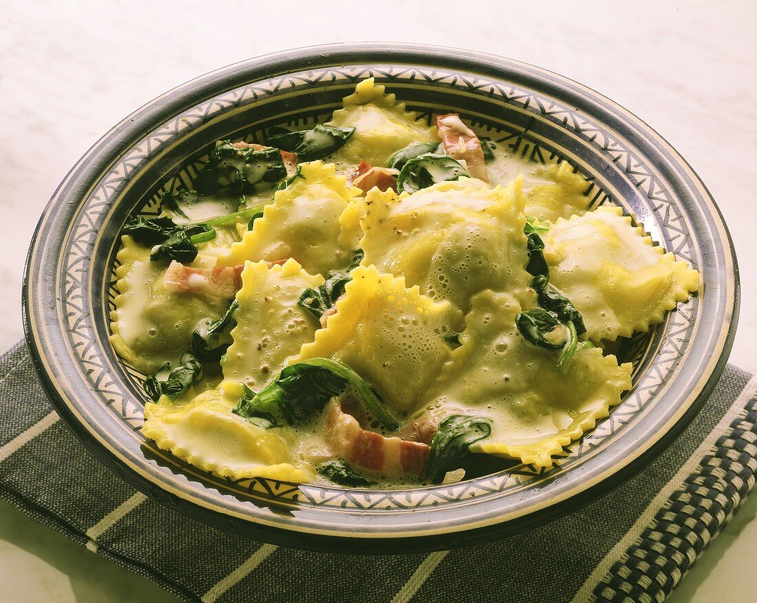 Ravioli with spinach, bacon and cream sauce on plate
