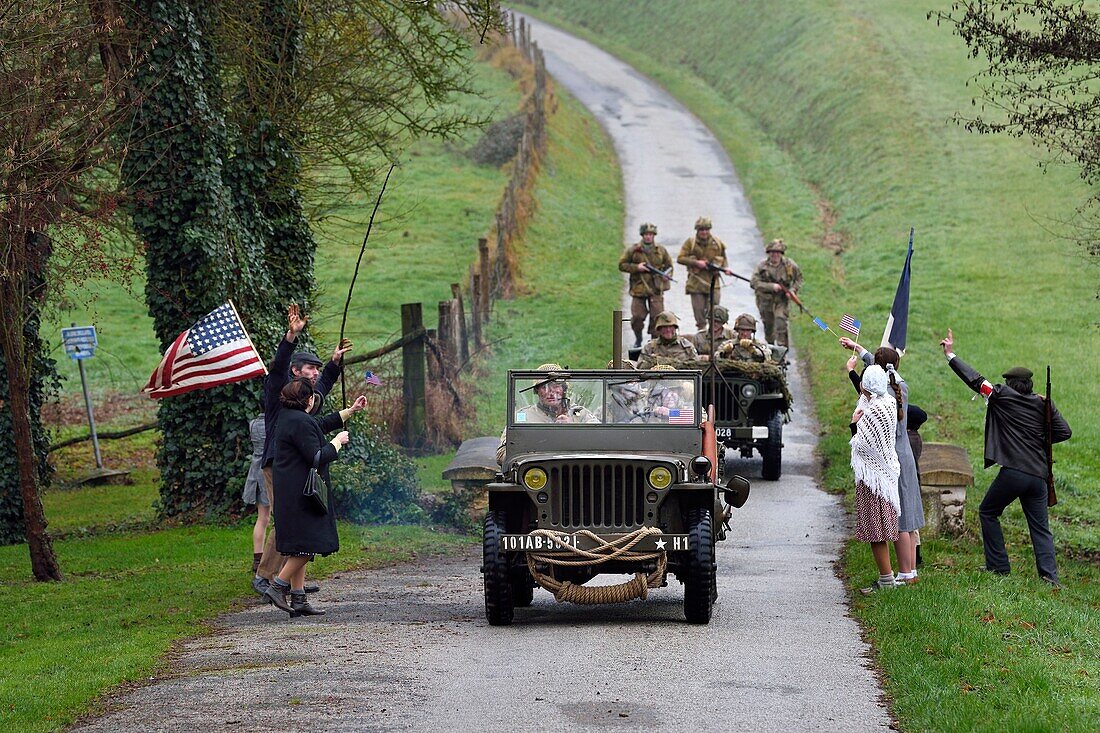 Frankreich,Eure,Sainte Colombe prés Vernon,Allied Reconstitution Group (US World War 2 and french Maquis historical reconstruction Association),Reenactors in Uniform der 101st US Airborne Division, die in einem Jeep Willys vorfahren und von Dorfbewohnern und FFI als Befreier begrüßt werden