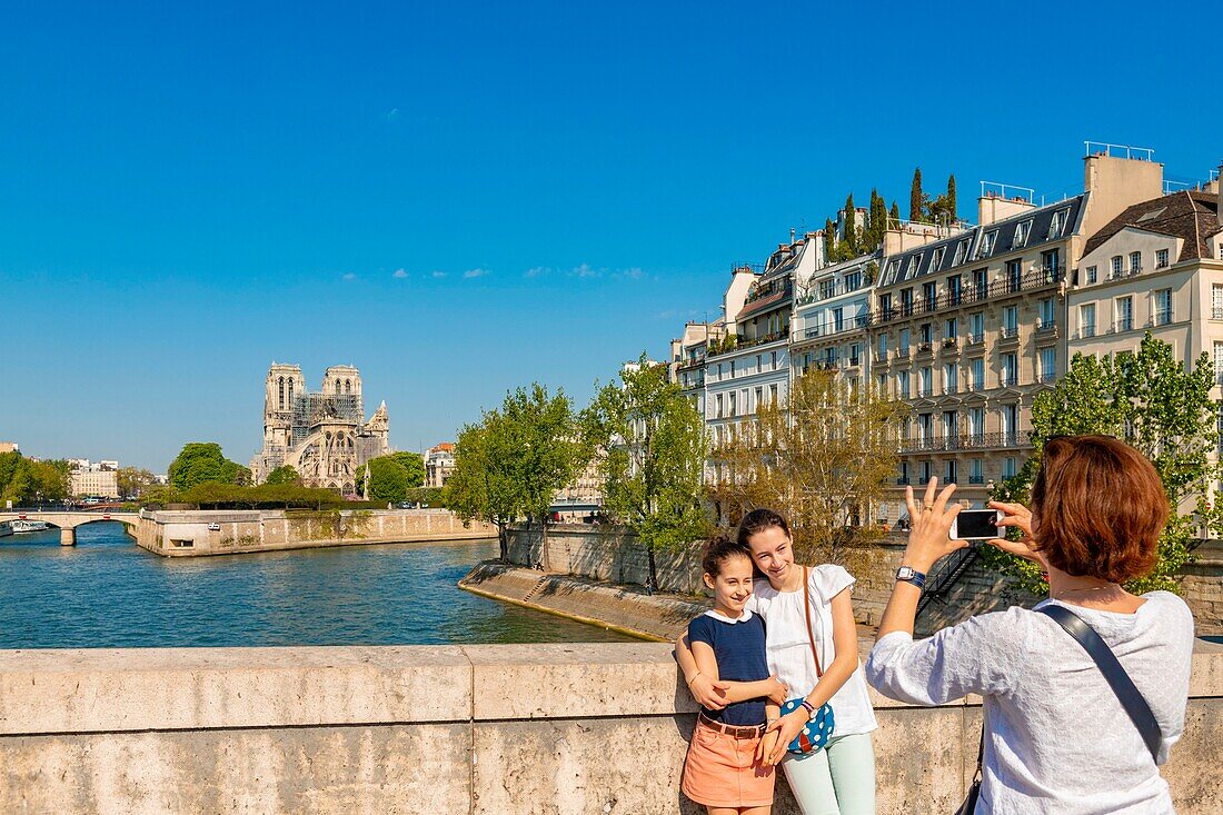 France,Paris,area listed as World heritage by UNESCO,Ile de la Cite,tourist photographing in front of Notre Dame cathedral