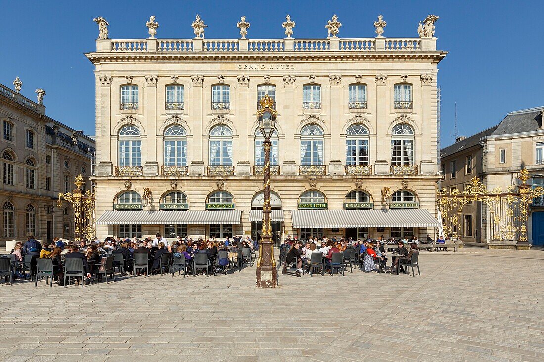 France,Meurthe et Moselle,Nancy,Stanislas square (former royal square) built by Stanislas Leszczynski,king of Poland and last duke of Lorraine in the 18th century,listed as World Heritage by UNESCO,terrace and facade of the Grand Hotel de la Reine,street lamps and railings ironworks by Jean Lamour,facade of the Opera house to the left