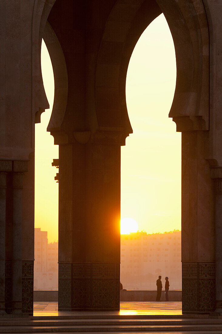 Marokko,Blick durch die Bögen der Hassan II Moschee auf ein plauderndes Paar,Casablanca