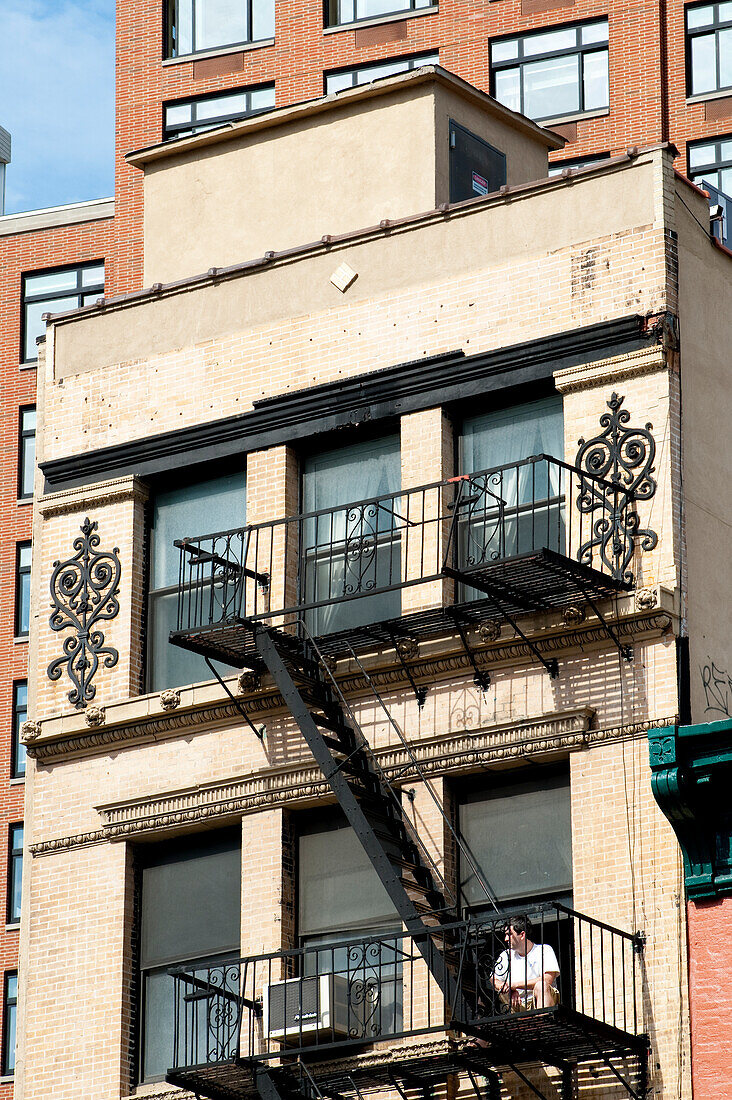 Mann sitzt vor einem traditionellen Wohnhaus in Tribeca, Manhattan, New York, USA