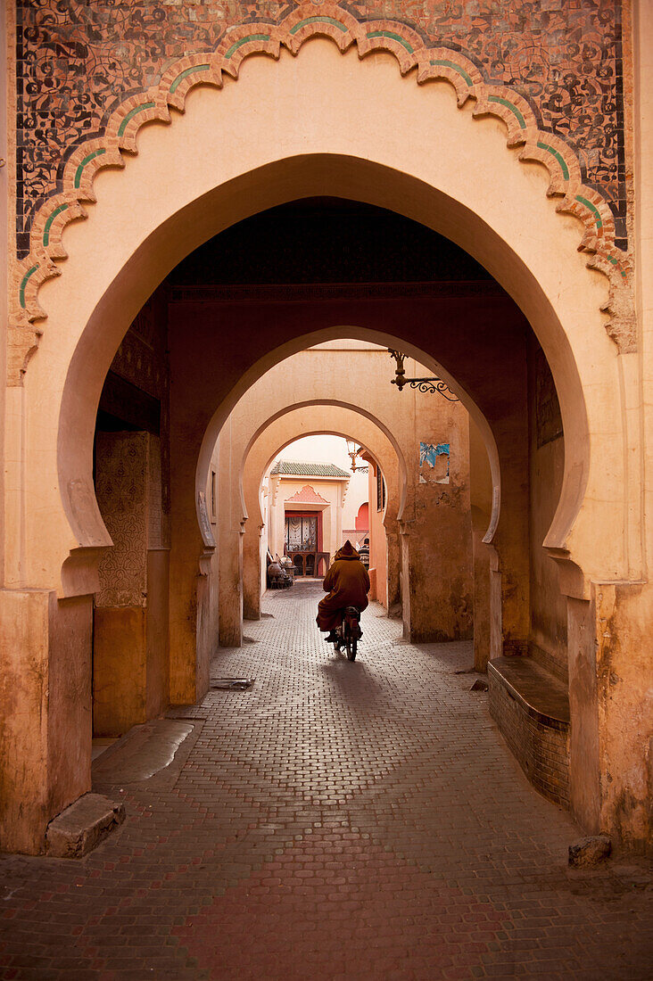 Morocco,Man on moped going through arches in alleyway in Medina of Marrakesh,Marrakesh