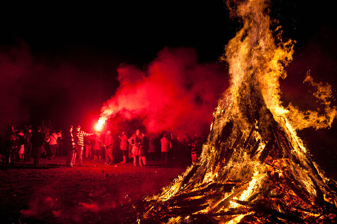 UK,England,Man with red flare beside large bonfire at Battle Bonfire night,East Sussex