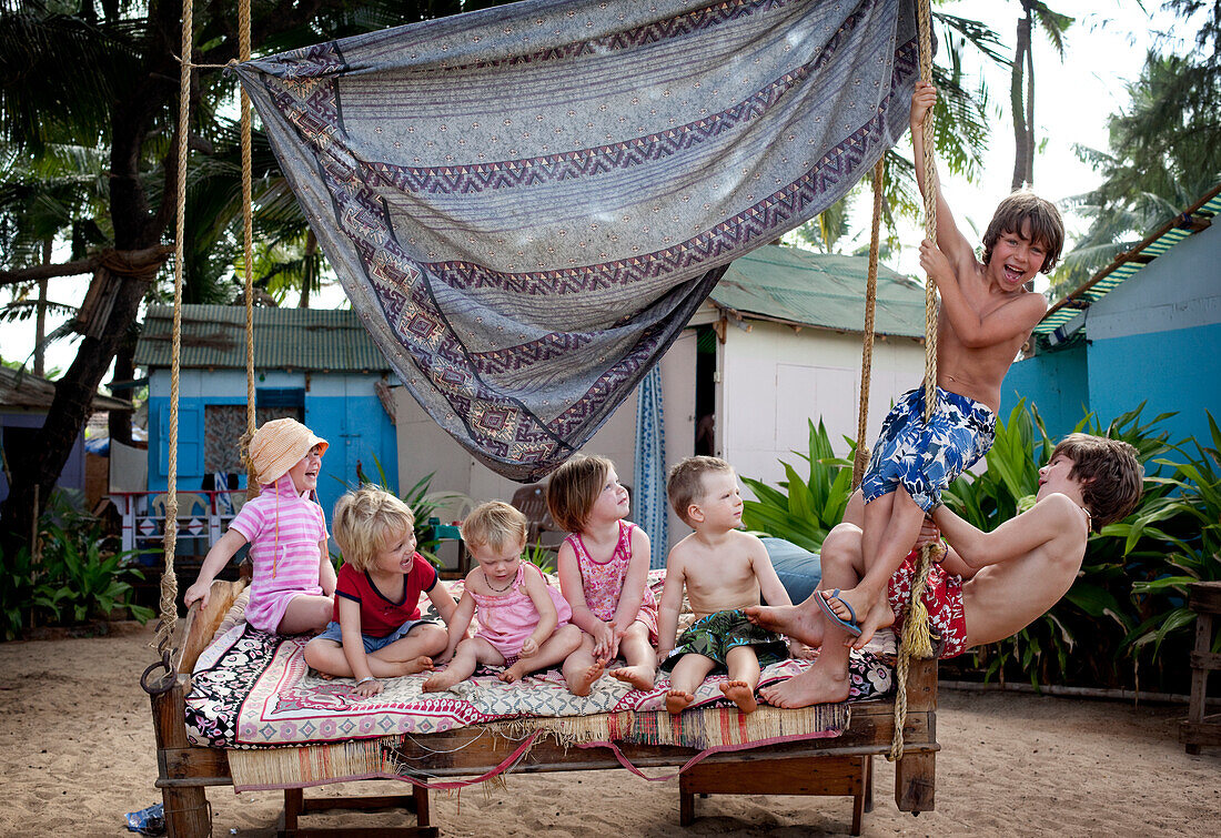 Kiki Lett aged 5,(left) and friends on holiday together play pirates on a swingbed (left to right) kiki Lett,Ivan Cumin,Myonie Reynolds,Lula Issac,Rudy Mchugh,Max Rollason and fred Grey ) in Solitude Restaurant and Huts,Patnum Beach,Goa,India. Pho