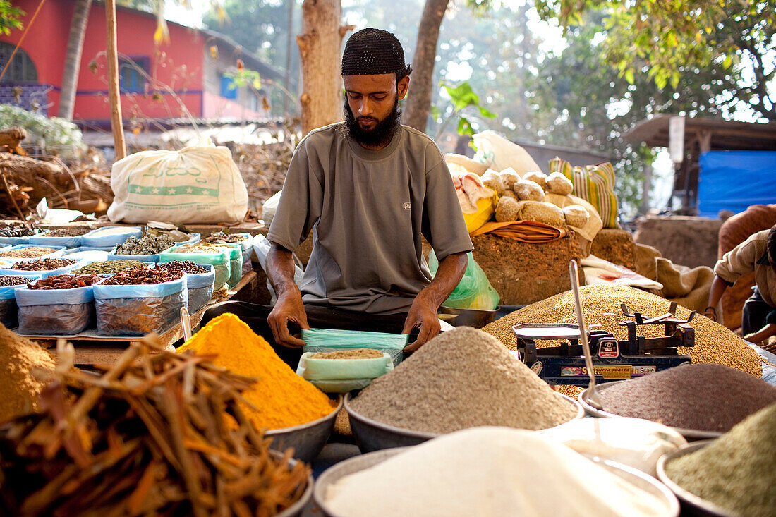 A vendor sits amongst his dried produce in Chaudi Market,Chaudi,Goa,India.