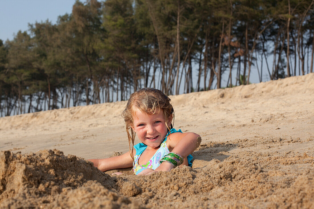 Sylvie Reynolds plays in a hole dug for her to sit in,Turtle Beach,Goa,India.