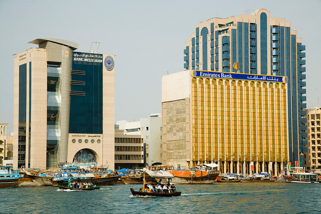 UAE,Bussling waterway traffic of Dubai Creek. Small ferries and fishing boats and private vessels crossing narrow waterway in Dubais centre. High Rise corporate buildings donimate the waterside skyline,Dubai