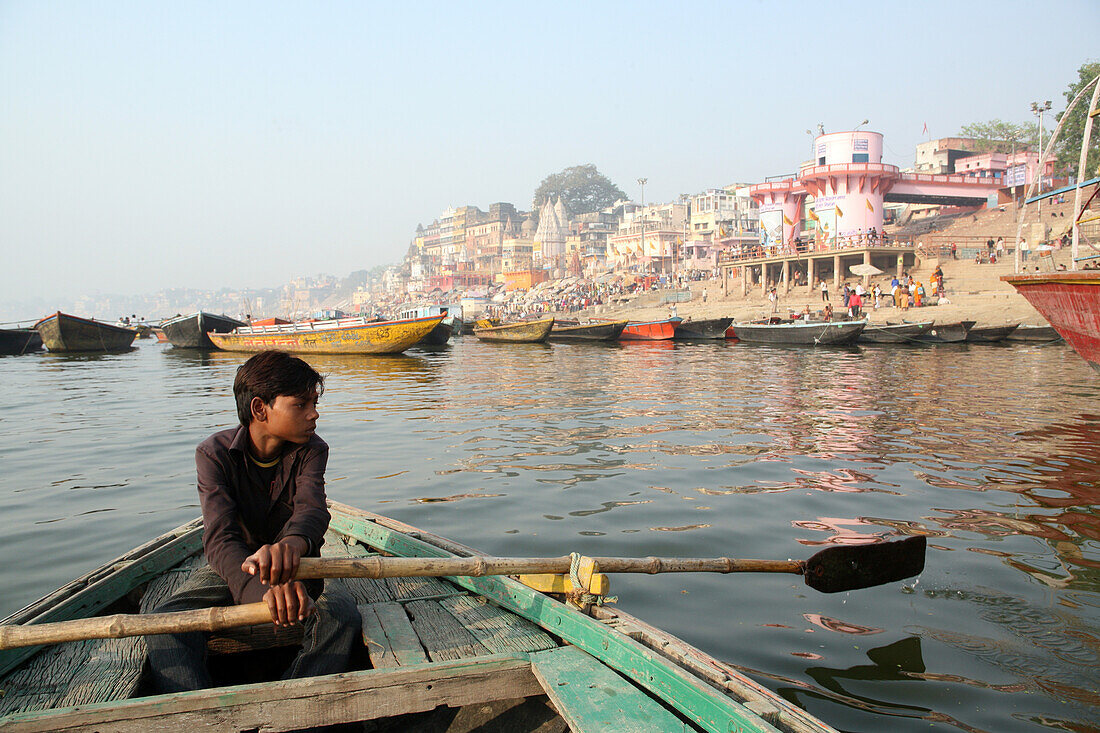 Boy rowing boat for tourists along River Ganges. The culture of Varanasi is closely associated with the River Ganges and the river's religious importance.It is 'the religious capital of India'and an important pilgrimage destination.Varanasi,also known as