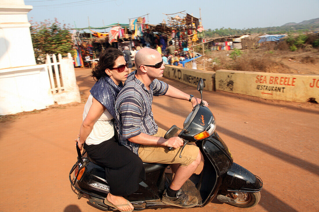 Tourists on scooters heading away from world famous Anjuna Flea Market,held on Wednesdays on Anjuna Beach,Goa State,India,Asia.