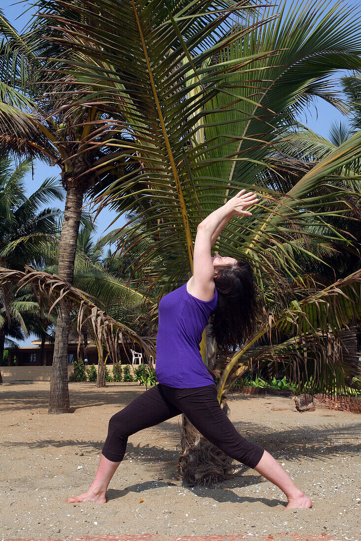 Trained yoga teacher doing yoga poses/ postures along Anjuna Beach. Goa State,India,Asia.
