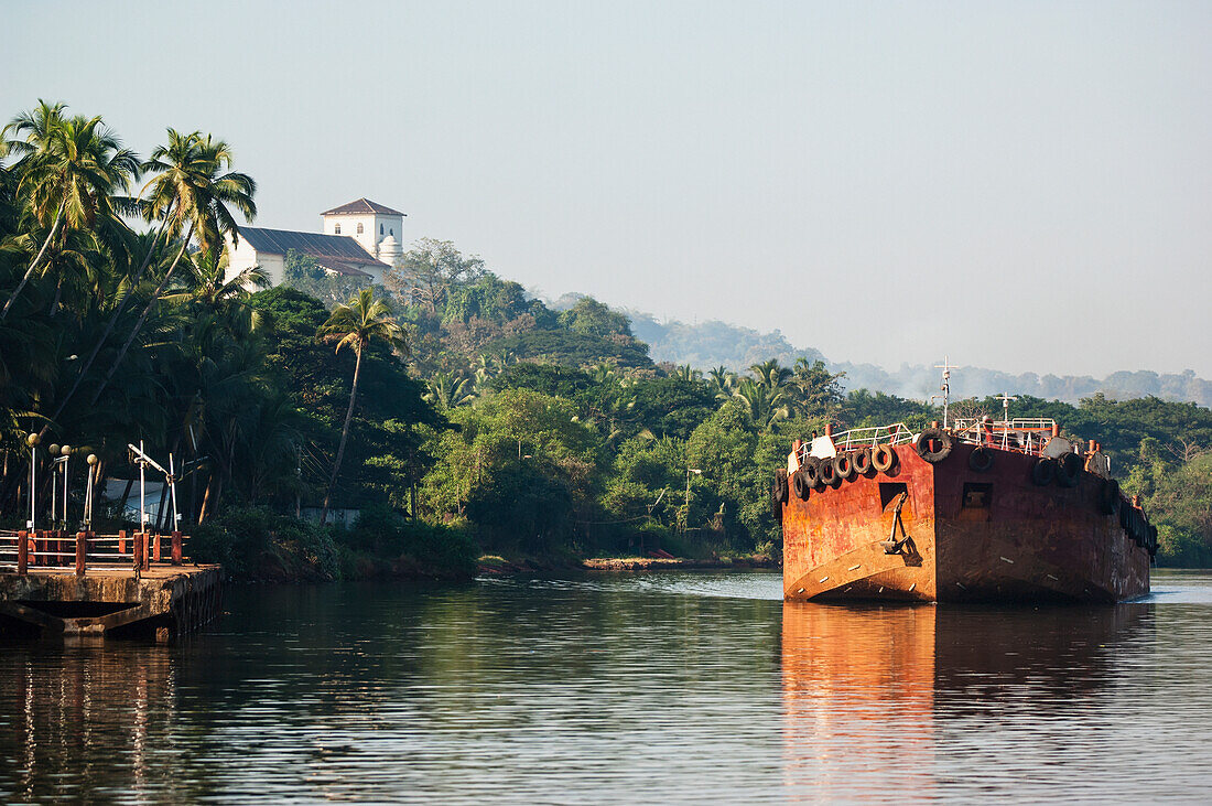 Indien, Frachtkahn auf dem Mandovi-Fluss mit der Kapelle von St. Catherine im Hintergrund, Alt-Goa