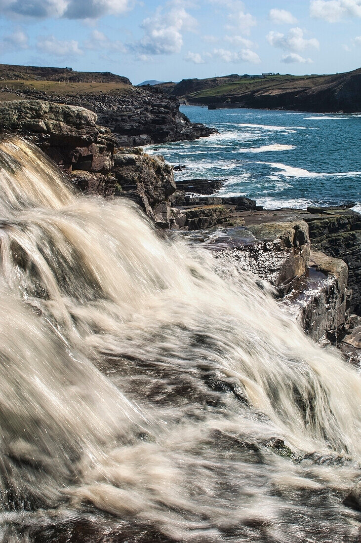 Peat colored water pouring into Cooncrome Harbor,Cahersiveen,County Kerry,Ireland,UK