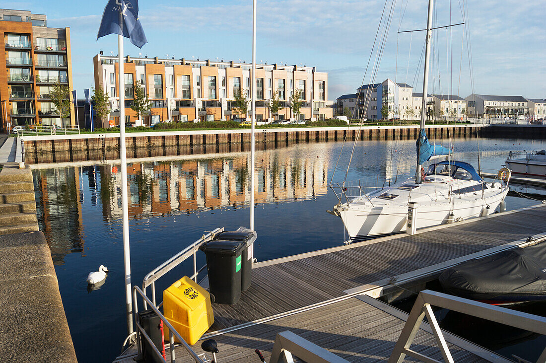 Buildings Reflected In The Water Along The Shoreline And A Sailboat Mooring In The Harbour,Portishead,North Somerset,England