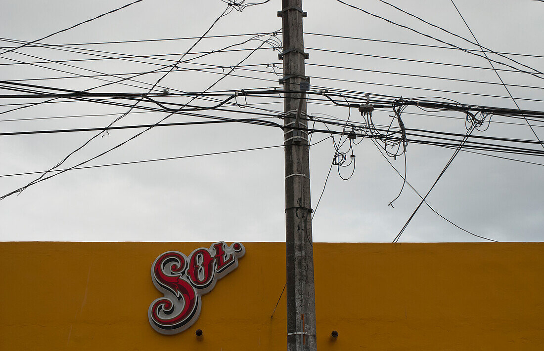 Elektrische Drähte und Telefonkabel mit einem Schild an einer gelben Wand,Tulum,Mexiko