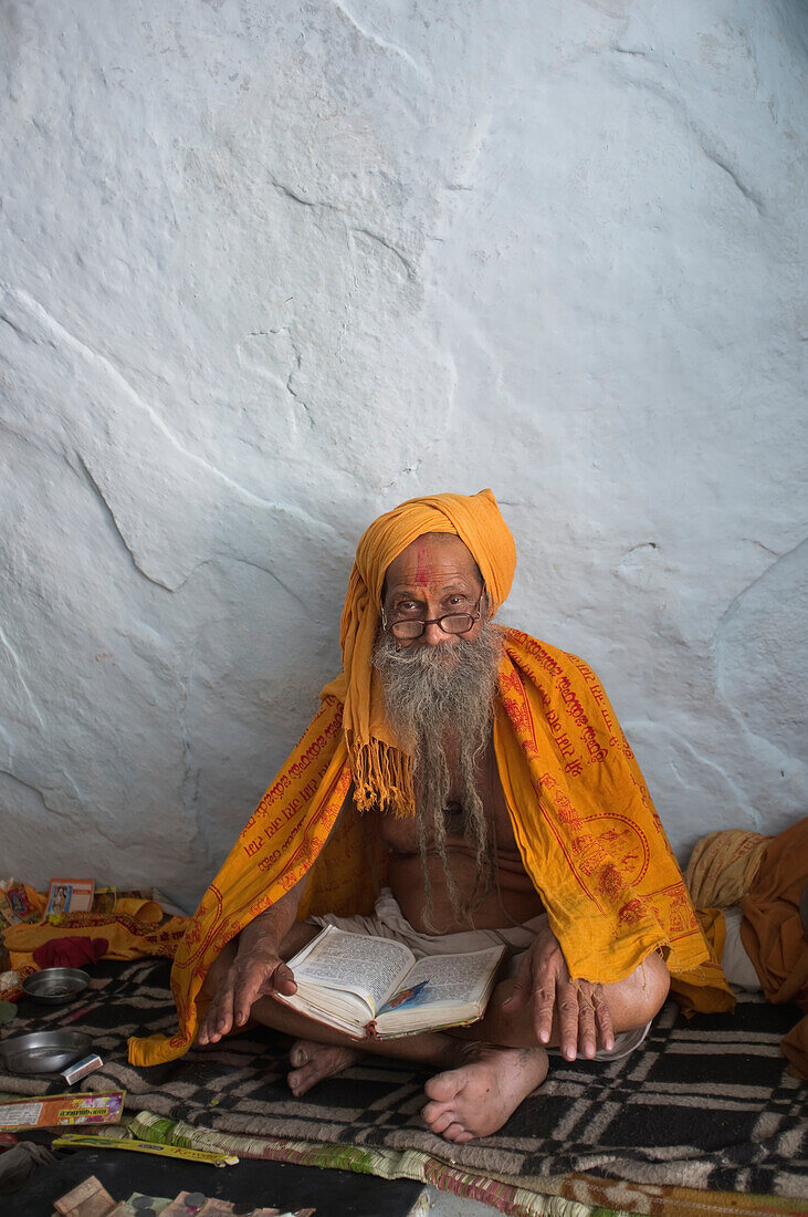 Ein älterer Mann sitzt und liest ein Buch, Hampi, Karnataka, Indien