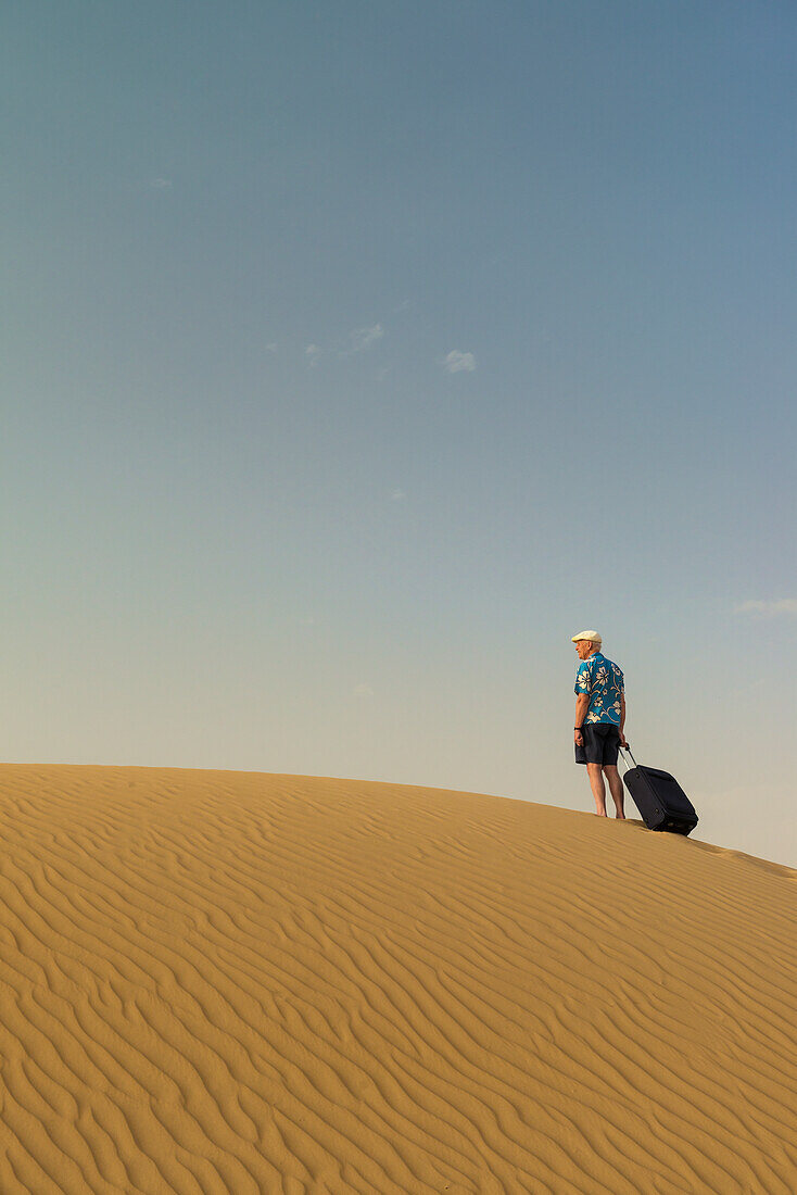 Barefoot Man With Suitcase On Sand Dune,Dubai,United Arab Emirates