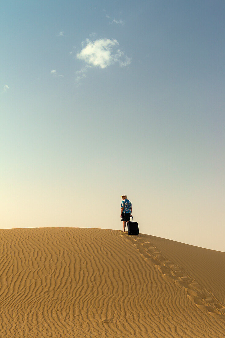 Barefoot Man With Suitcase On Sand Dune,Dubai,United Arab Emirates