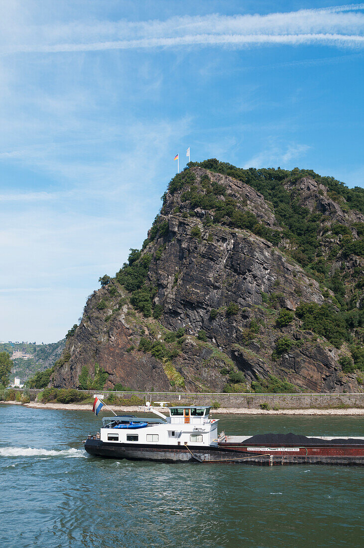 Ein Lastkahn fährt den Rhein hinunter, am Loreley-Felsen vorbei, Deutschland