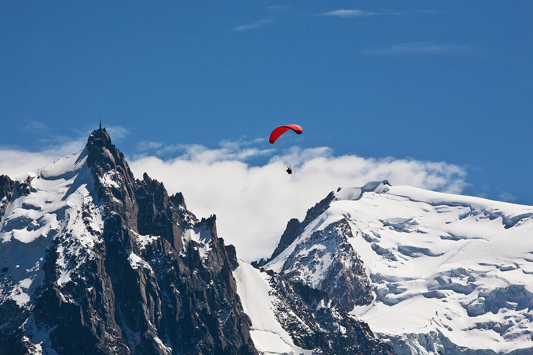 Gleitschirmflieger über dem Chamonix-Mont-Blanc-Tal, mit dem Mont-Blanc-Massiv und der Aiguille Du Midi im Hintergrund, Frankreich