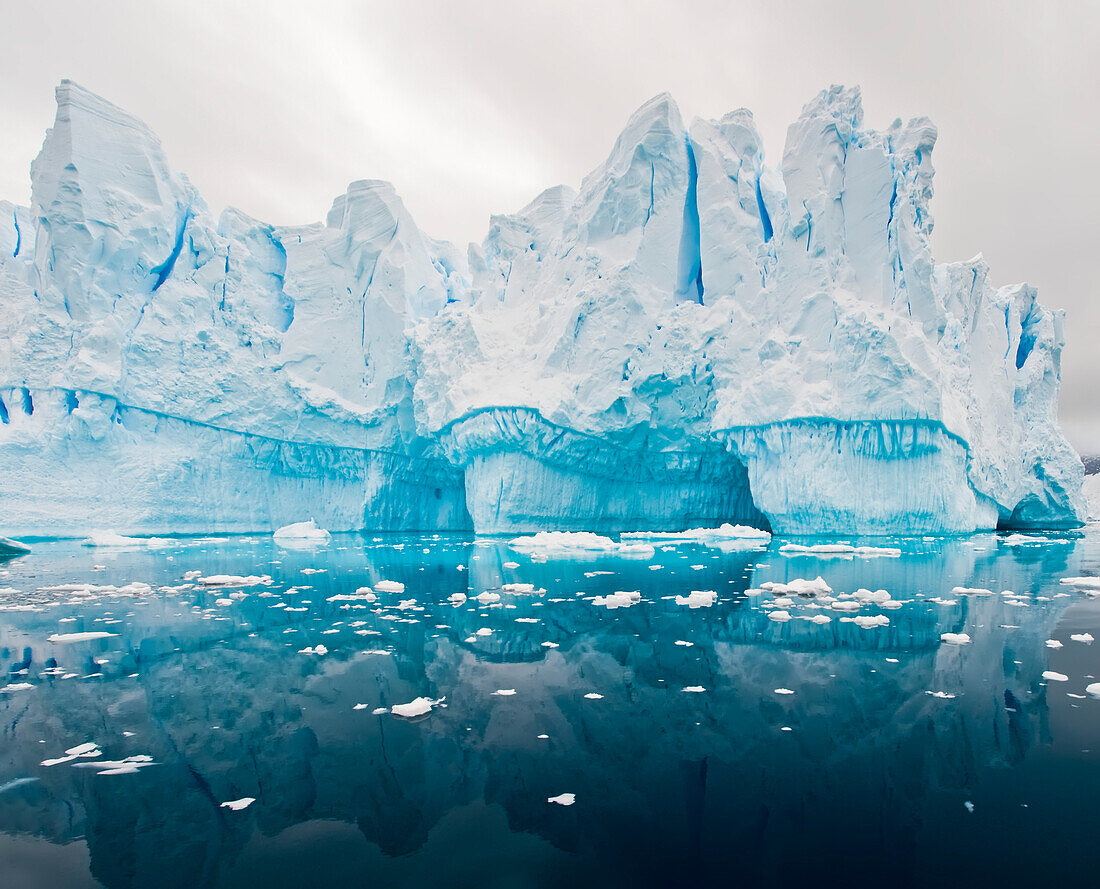 Meereis schwimmt im Neko-Hafen im Südpolarmeer, mit Tunneln, die sich im blauen Eis im Hintergrund gebildet haben, Antarktis
