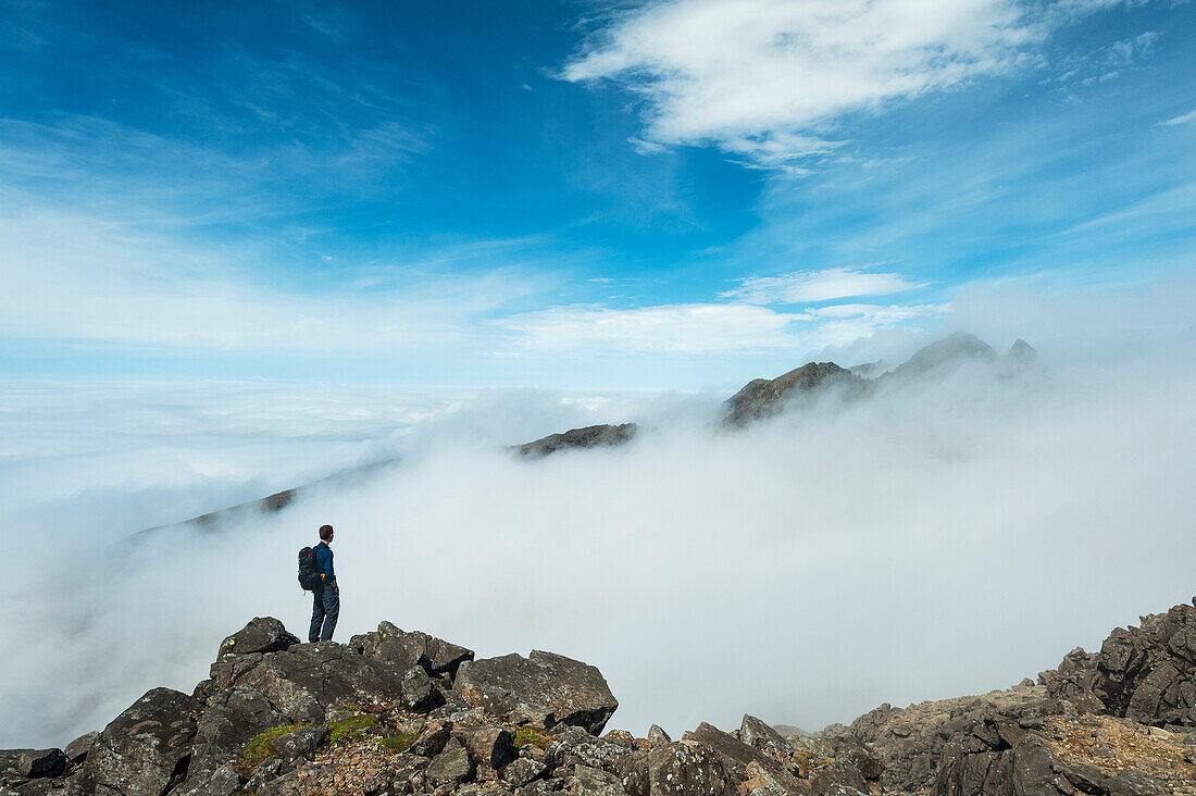 Ein Wanderer bewundert die Aussicht von der Spitze von Sgurr Nan Eag, einem der Gipfel der Black Cuillin, Isle Of Skye, Schottland