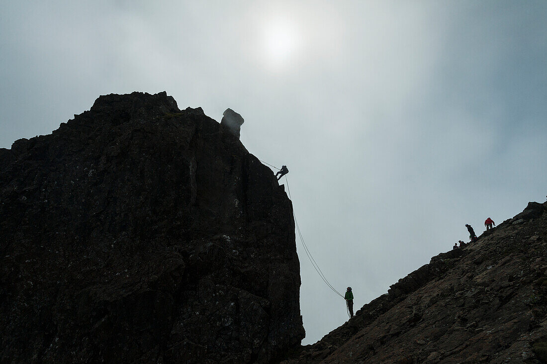 Silhouette von Menschen, die sich von der unzugänglichen Zinne am Gipfel des Sgurr Dearg abseilen, Isle Of Skye, Schottland