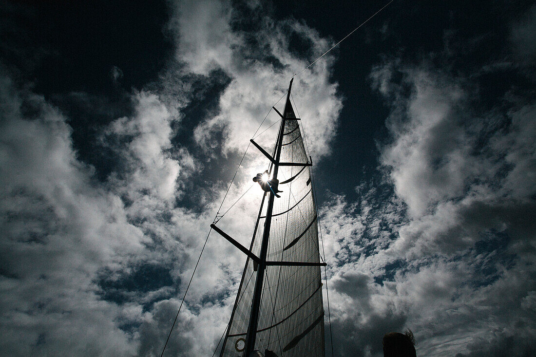 Silhouette eines Mannes, der auf einen Segelmast klettert, vor einem blauen, wolkenverhangenen Himmel mit Sonnenuntergang beim Mt Gay Rum Yacht Race, das die Insel Grenada umrundet,Grenada,Karibik